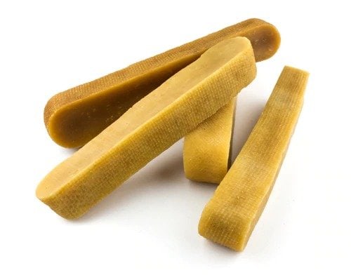 A pile of dry, uncooked pasta resembling large flat noodles on a white background.
